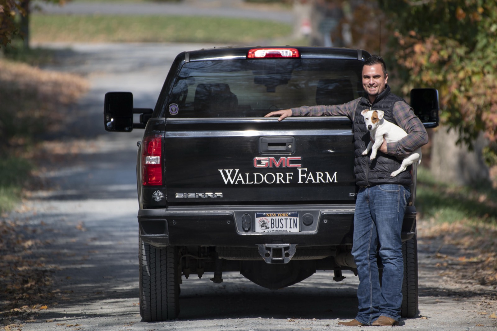 Kenny Toye, farm manager, holding a terrier beside the Waldorf Farm truck on the farm lane